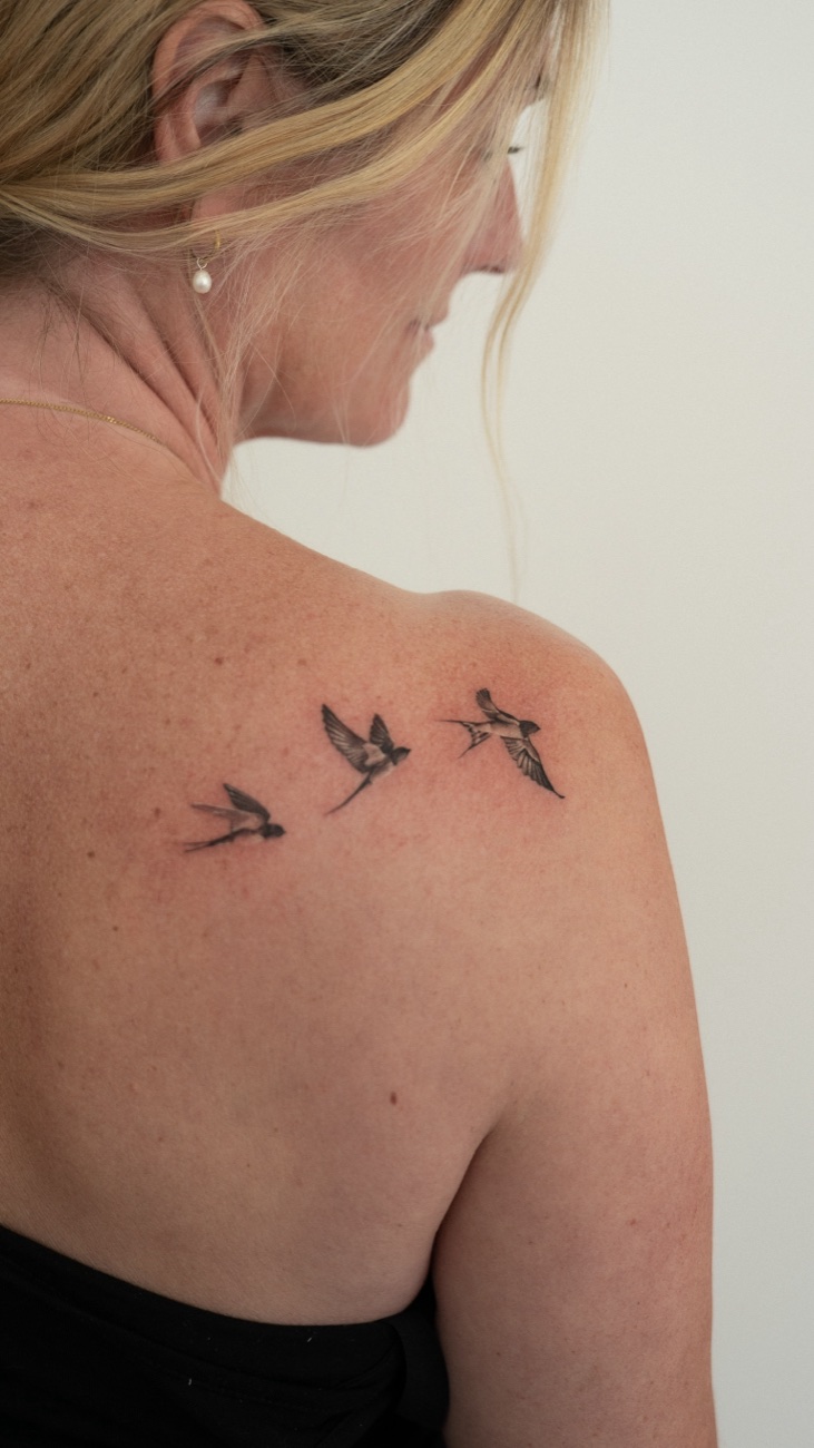 Fine line flock of birds tattoo on a shoulder