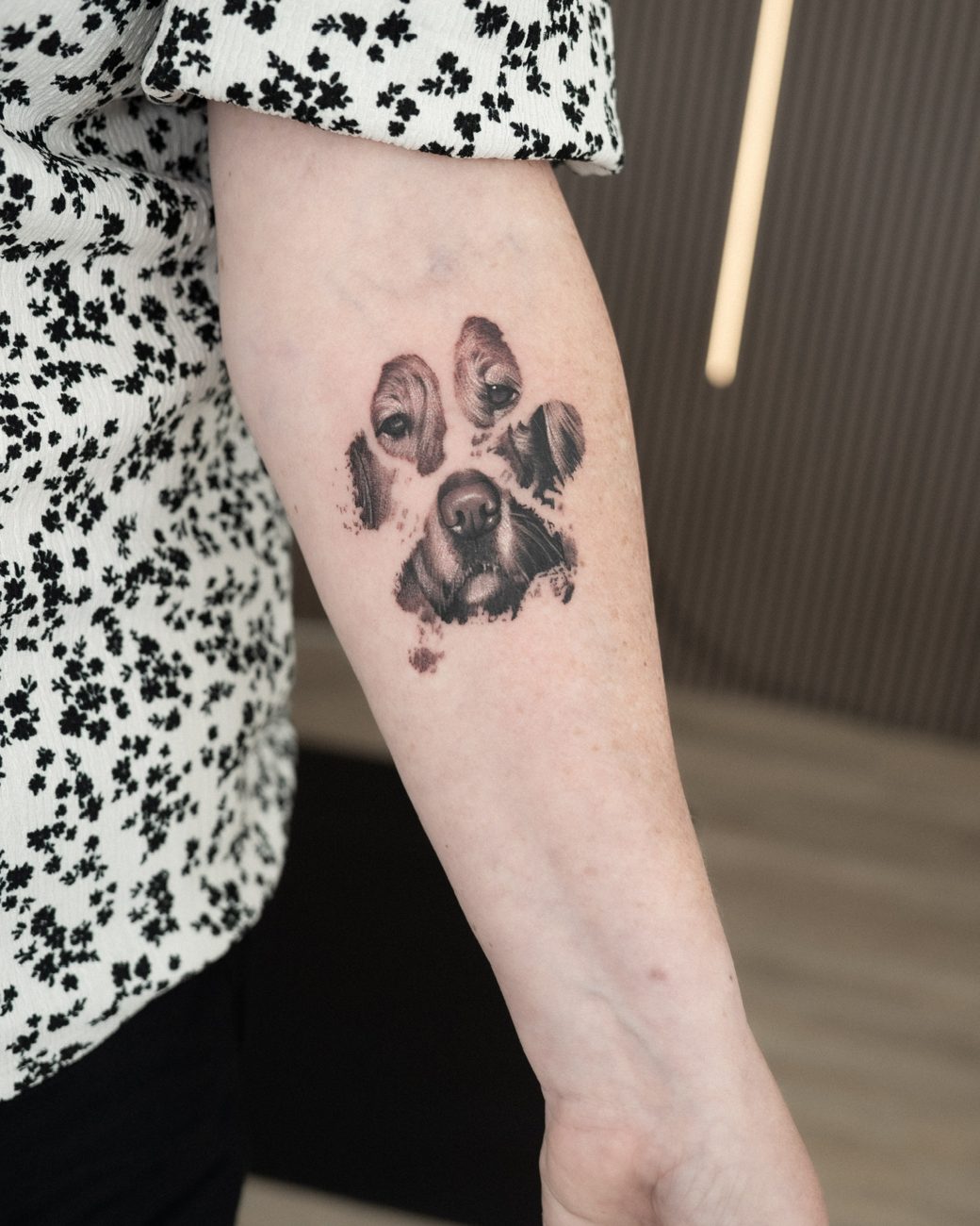 Realism paw print tattoo with a dog portrait detail on a forearm